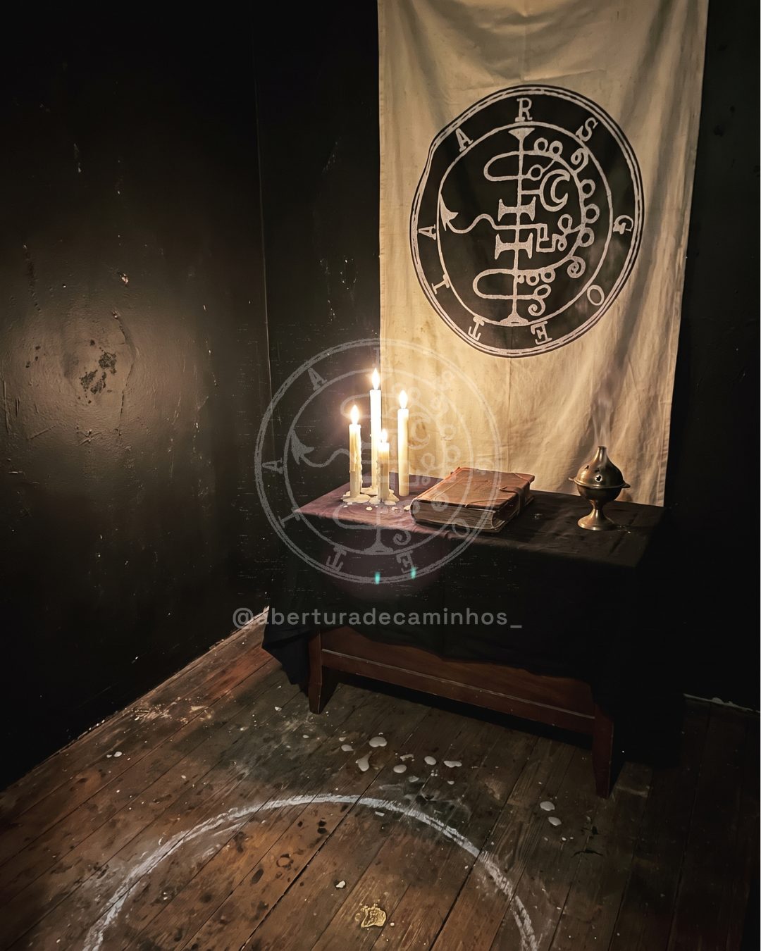 Interior do templo: altar com velas, grimório e estandarte com o sigilo